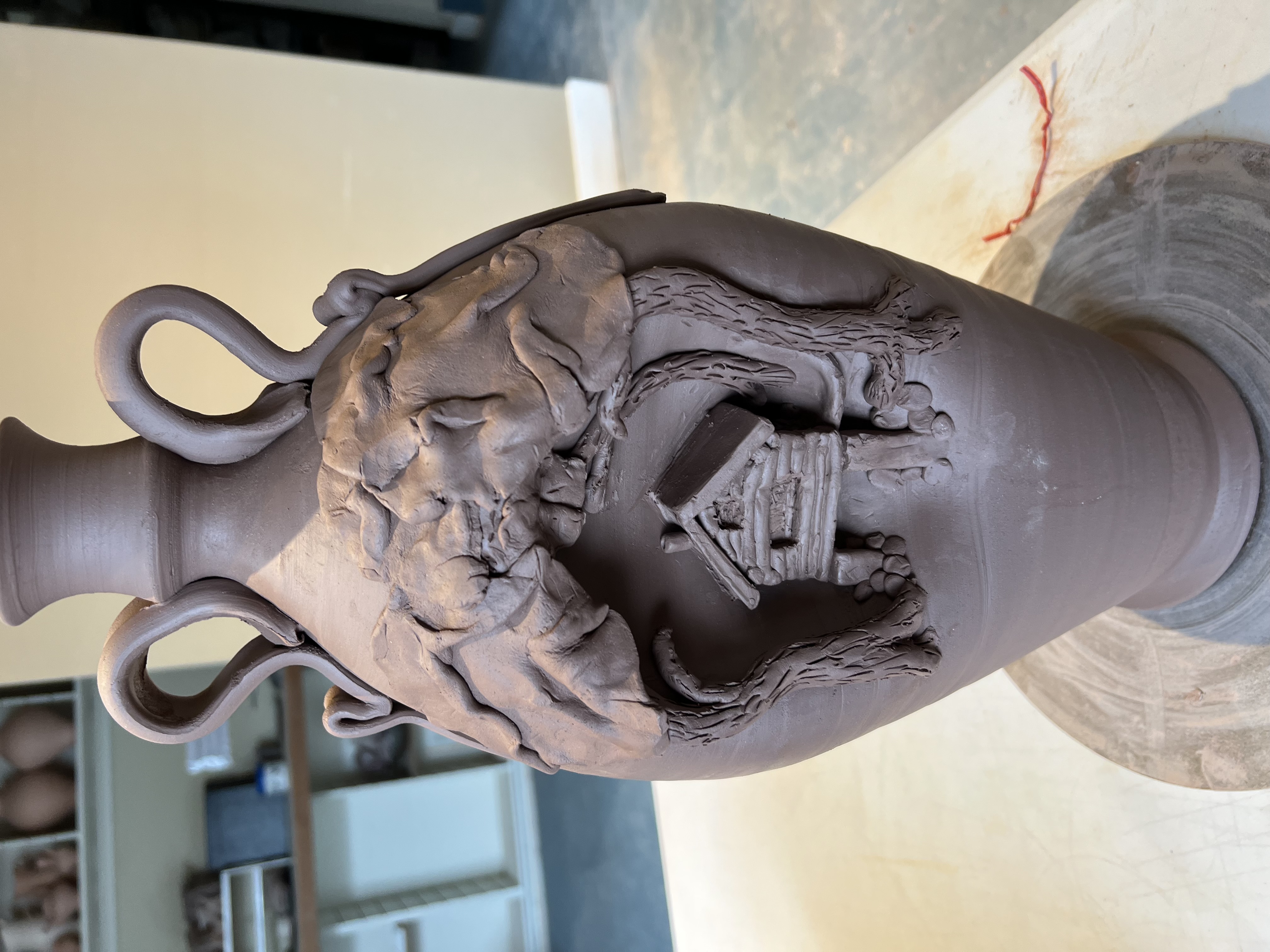 Unfired sculptural vessel with house and tree relief